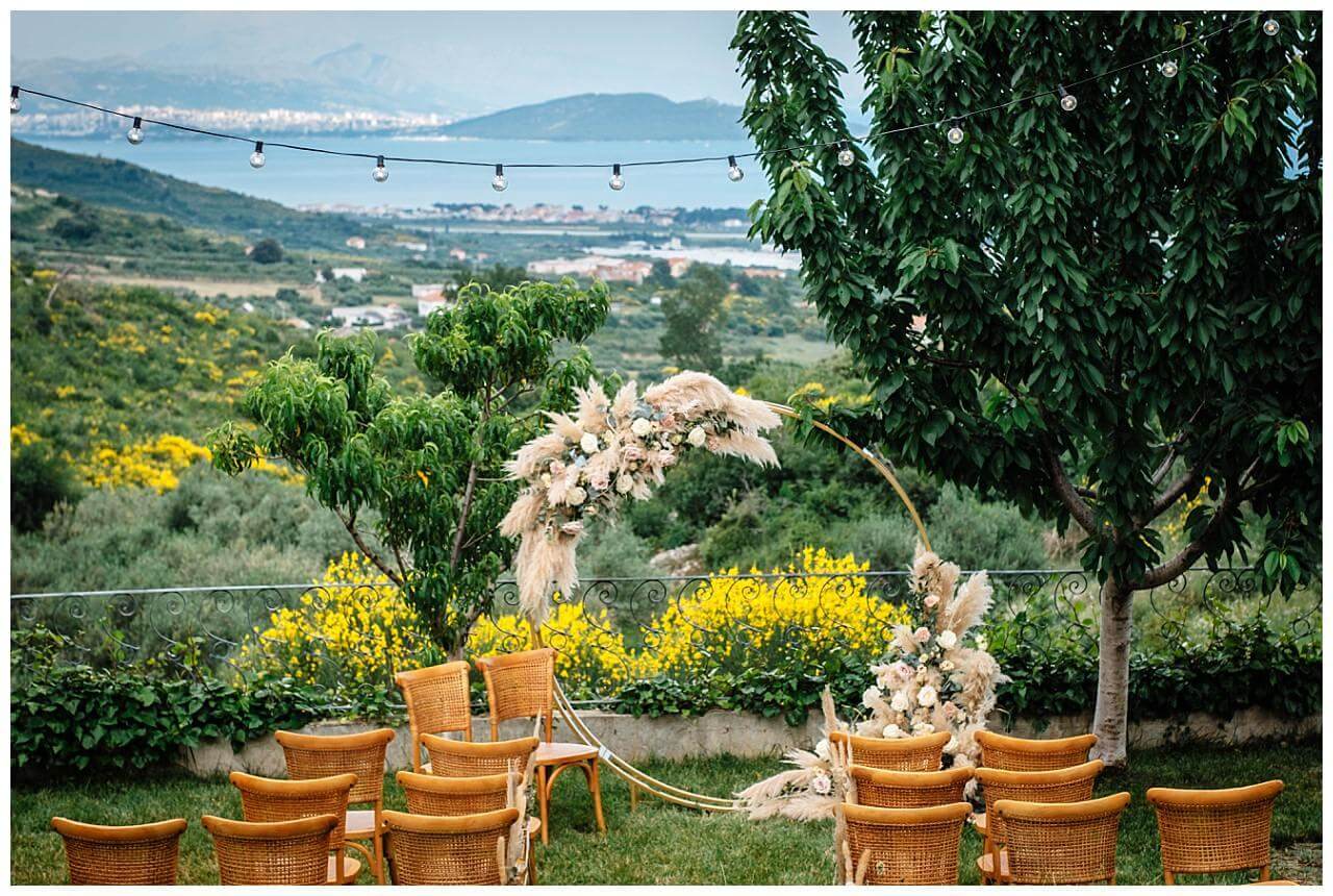 Traubogen aus Holz mit Blumenschmuck in beige und blassen rosa mit Federn bei einer Hochzeit in Istrien Kroatien
